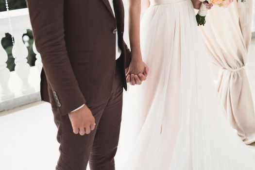 Bride and groom hold hands during the wedding ceremony