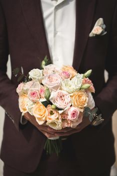 Beautiful bouquet of colorful roses in the hands of the groom.
