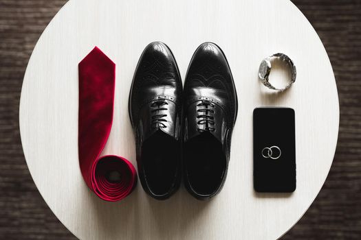 Groom is gathering in the morning.Men's classic shoes, belt,toilette, perfume, leather strap watch, wedding rings.