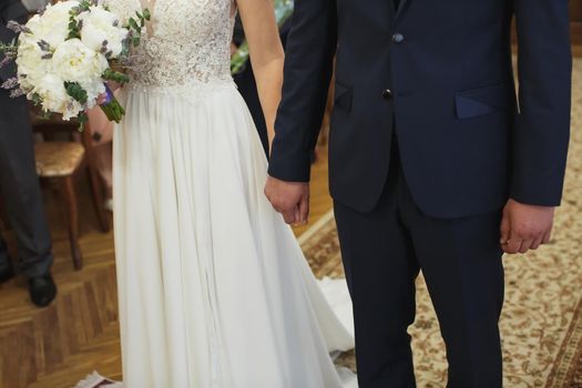 Bride and groom in the registry office holding hands