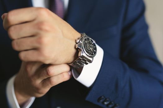 Close-up hands of the groom with a clock