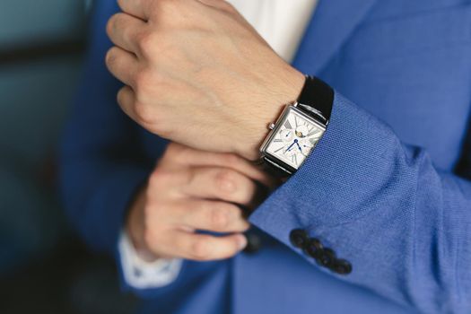 Close-up hands of the groom with a clock