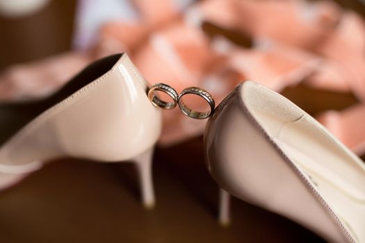 Gold wedding rings between the bride 's wedding shoes