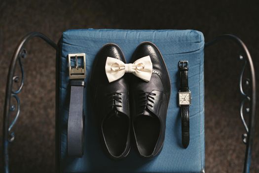 Men's shoes , watch, belt, tie and rings on a chair. The view from the top