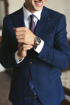 Close-up hands of the groom with a clock