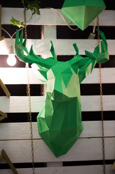 Green deer head made of paper on the wall.