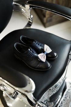 Shoes, watch, tie on the chair. The groom is going to the barbershop in the morning