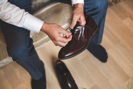 Groom putting his wedding shoes. Hands of wedding groom getting ready