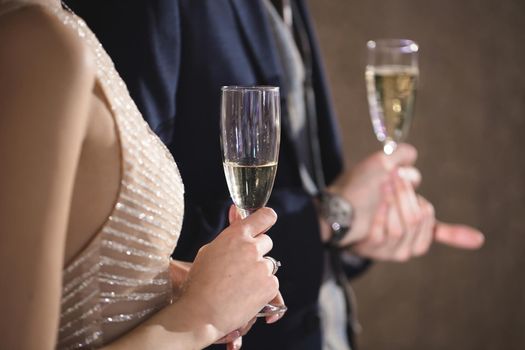 The bride and groom hold crystal glasses filled with champagne