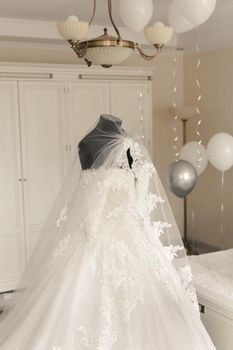 Chic wedding dress and veil on a mannequin in the bride 's gathering room