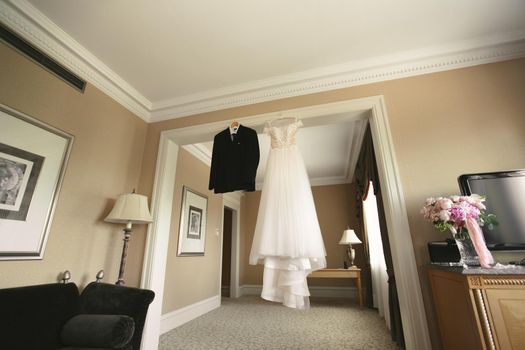 Dress of the bride and groom's suit hang on a hanger
