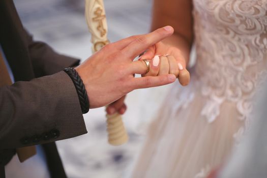 The groom puts the ring on the bride's finger in close-up