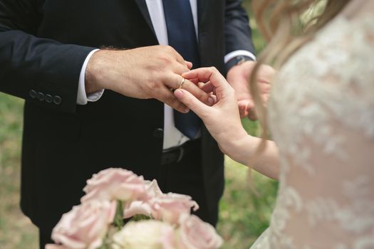 The bride puts a ring on the groom's finger in close-up