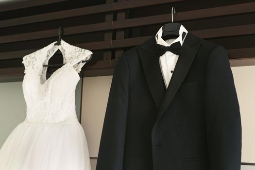 Dress of the bride and groom's suit hang on a hanger