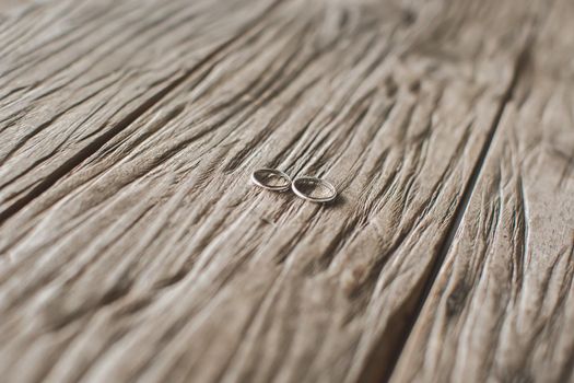 Macro shooting of gold wedding rings on the texture of wood.