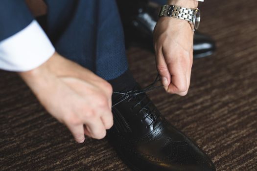 Man tying shoes laces on the wooden floor