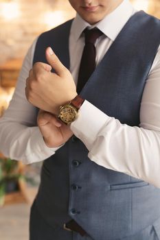 Close-up hands of the groom with a clock