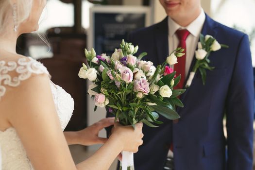 Wedding bouquet of white and lilac flowers in the hands of the bride.