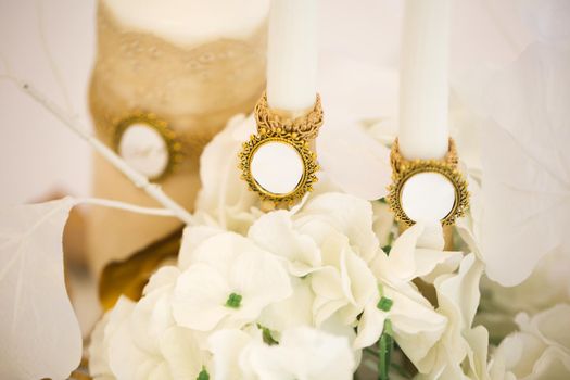Wedding decor in white and gold style with crystals, lace and flowers. Wedding candles for the family hearth