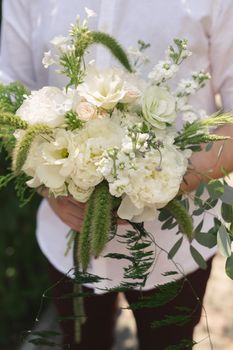 Beautiful bouquet of white and green flowers in the hands of the groom.