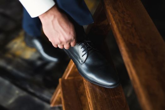 Man tying shoes laces on the wooden floor