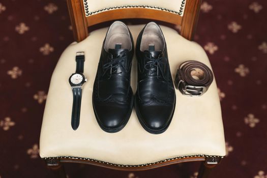 Groom is gathering in the morning.Men's classic shoes, belt,toilette, perfume, leather strap watch, wedding rings.