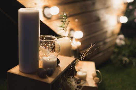 Beautiful wooden photo zone in the shape of a heart with glowing bulbs, candles and a gypsophile in a vase.