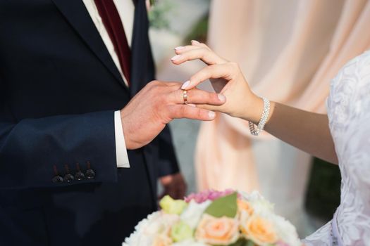 The bride puts a ring on the groom's finger in close-up