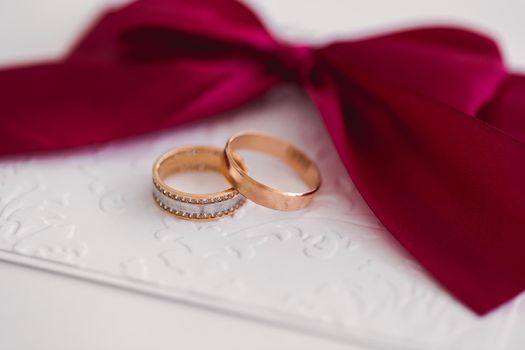 Gold wedding rings on a white card with a red bow