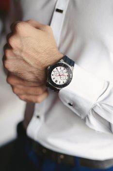 Close-up hands of the groom with a clock
