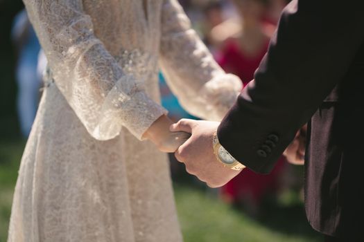 Bride and groom hold hands during the wedding ceremony