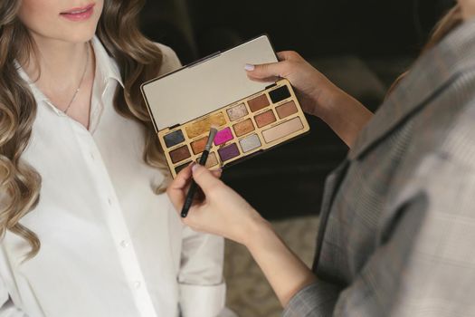 Young beautiful bride applying wedding makeup from a makeup artist. The morning training.