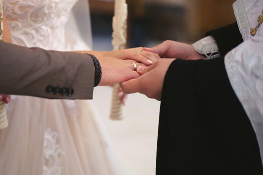 The priest consecrates the wedding rings on the fingers of the bride and groom. Wedding tradition and ritual. hands of a young couple in the church.