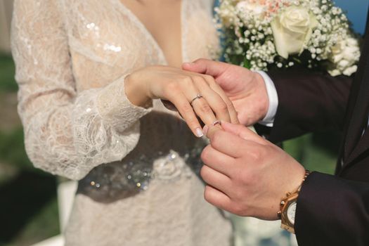 The groom puts the ring on the bride's finger in close-up