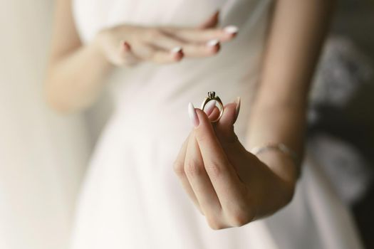 Close-up of the ring in the hands of the bride, who tries it on.
