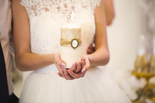 Wedding ceremony, paraphernalia, the bride and groom hold a large candle in their hand