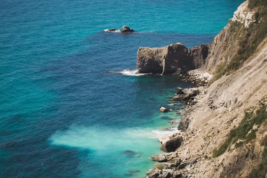 View of uplifted vertical sedimentary rock jutting out into the ocean.