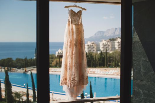 Wedding dress at the hotel on the background of the pool, ocean and mountains.