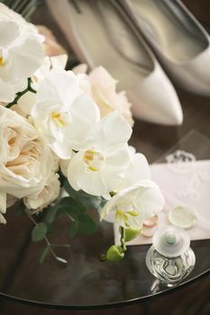 Elegant bouquet of roses and orchids, shoes and accessories of the bride close-up.