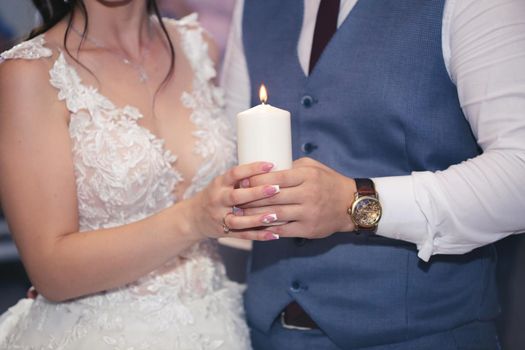 Wedding ceremony, paraphernalia, the bride and groom hold a large candle in their hand