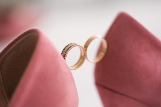 Gold wedding rings between the bride 's wedding shoes