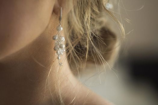 Long earring with violet precious stones hang from woman's ear