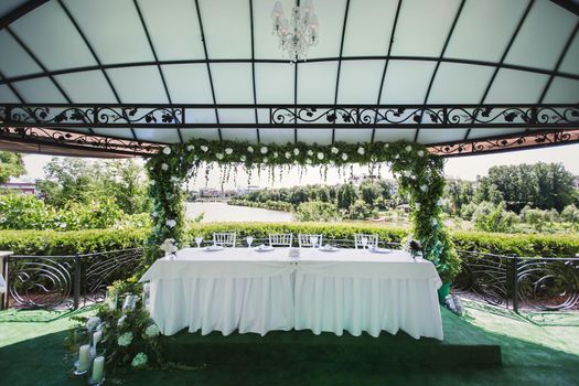 Wedding flower table decoration with candles on a green background of nature.