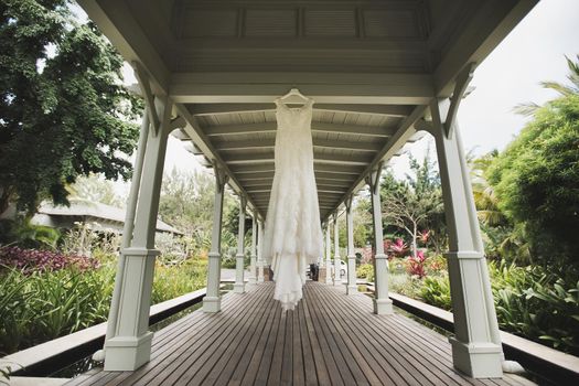 A luxurious wedding dress is hanging in the gazebo on the wedding day.