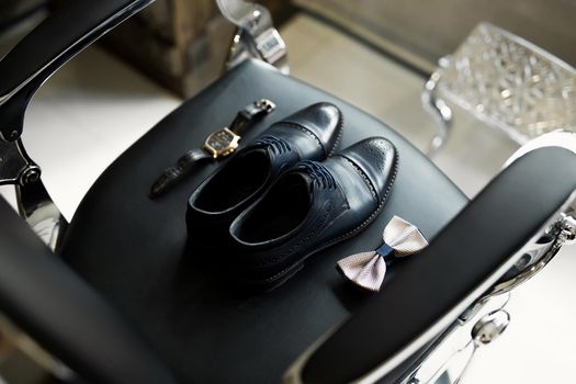 Shoes, watch, tie on the chair. The groom is going to the barbershop in the morning