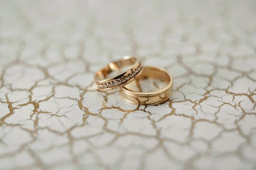 Close-up of wedding rings on cracked plaster.