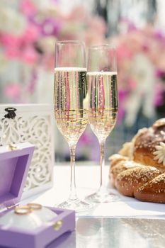 A box with wedding rings and gold sequins, champagne glasses, flowers.