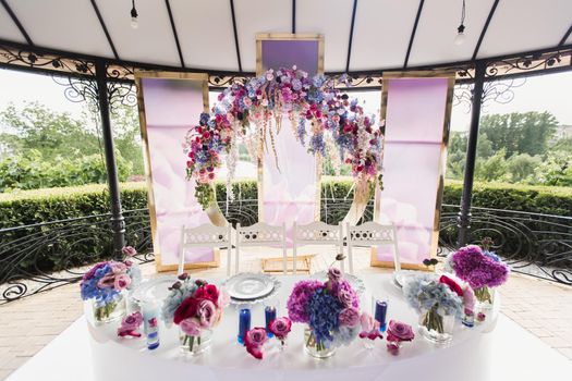 Bride and groom table setting and flower decoration. Presidium of newlyweds outdoors.