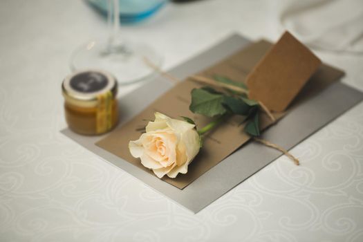 A nameplate on the wedding table with a live rose.