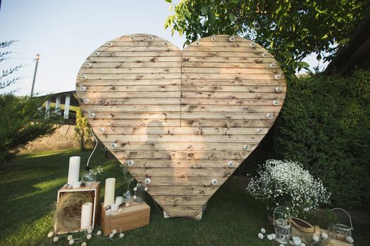 Wooden arch in the shape of a heart at an off-site wedding ceremony.